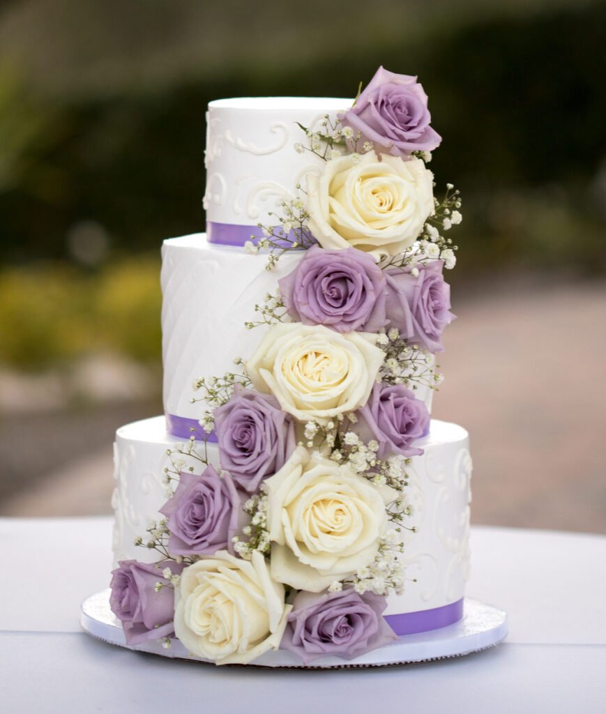 Three tiered wedding cake with lilac and cream roses and purple